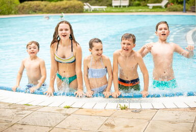 Kinder am Beckenrand im Aussenpool